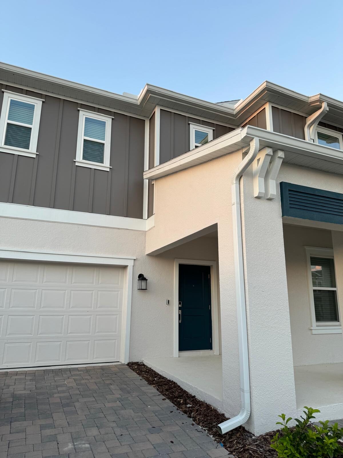 White gutters, fascia brackets and a downspout finished along the entry and garage of a two-story townhome