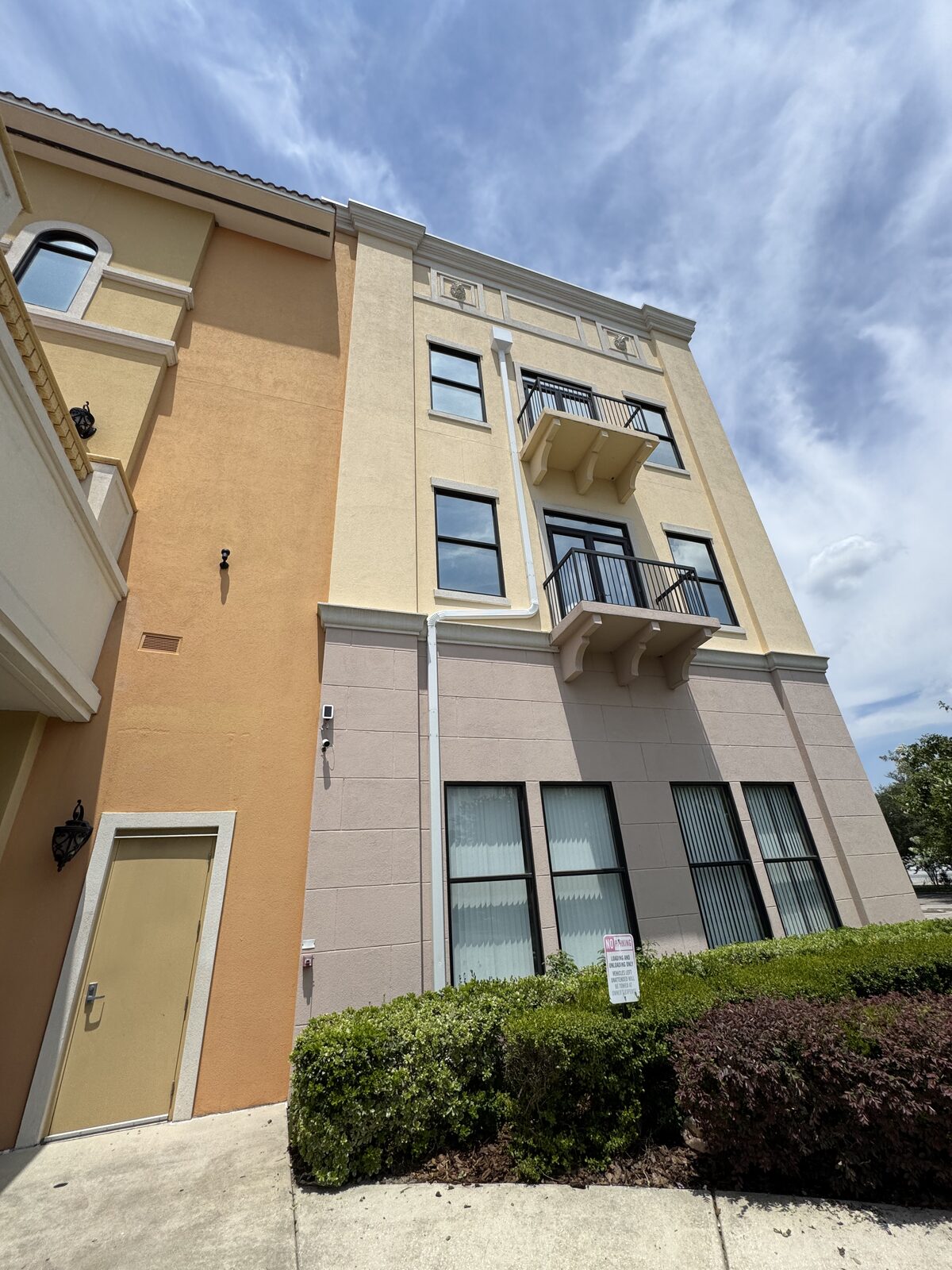 Full-height white downspout running down the exterior of a multi-story commercial stucco building