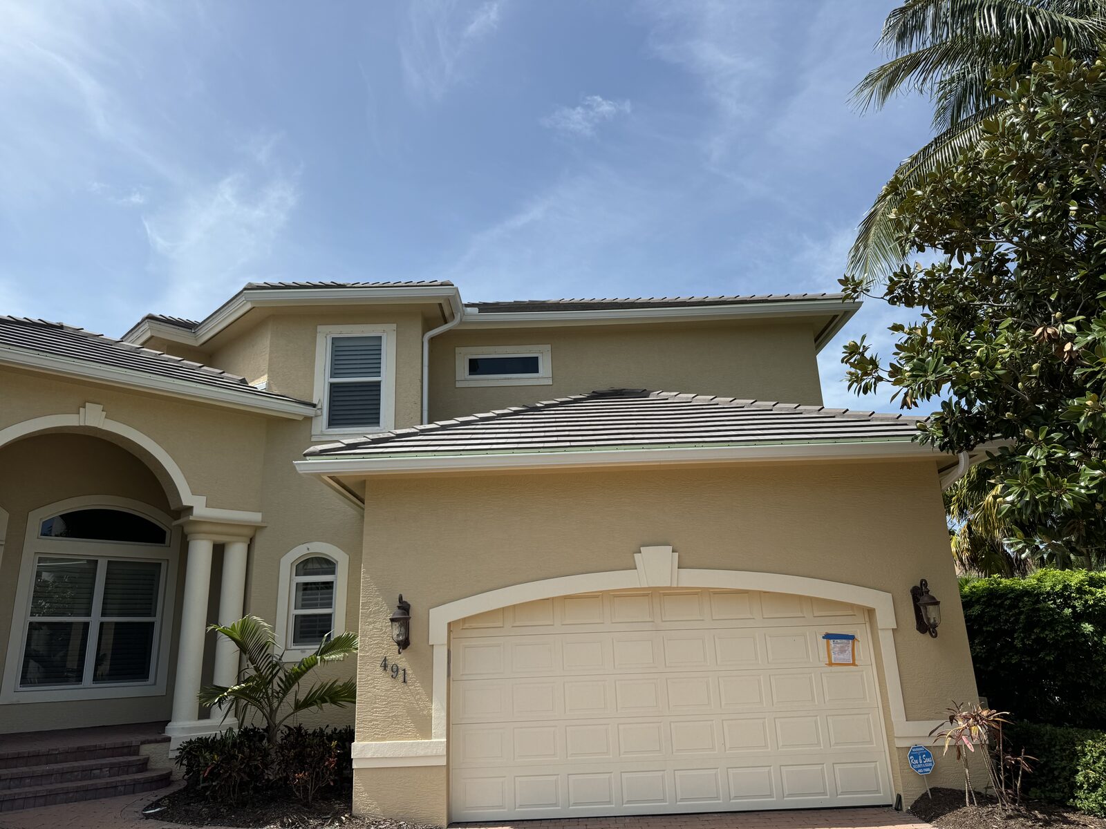 Gutter line finished along the tile roof above the garage and second story of a tan stucco home