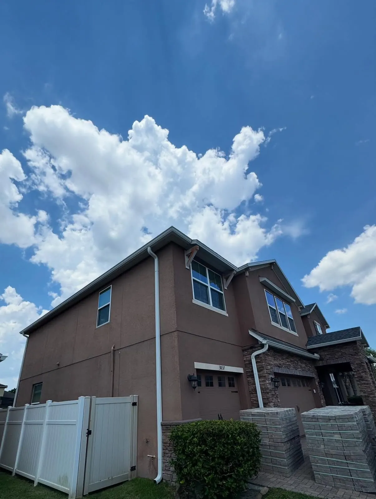 Large two-story brown stucco home with gutters