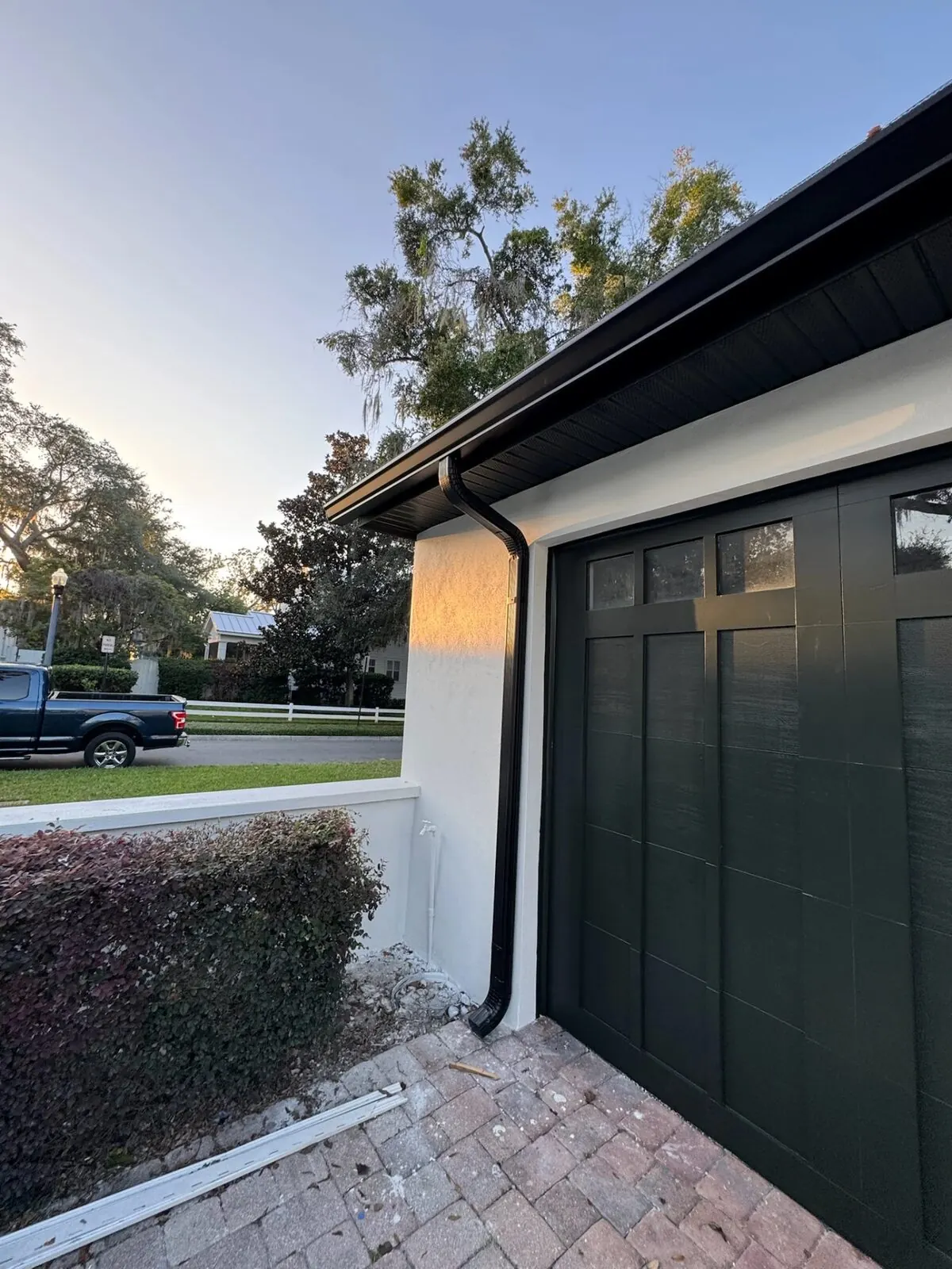 Black downspout beside a dark garage door