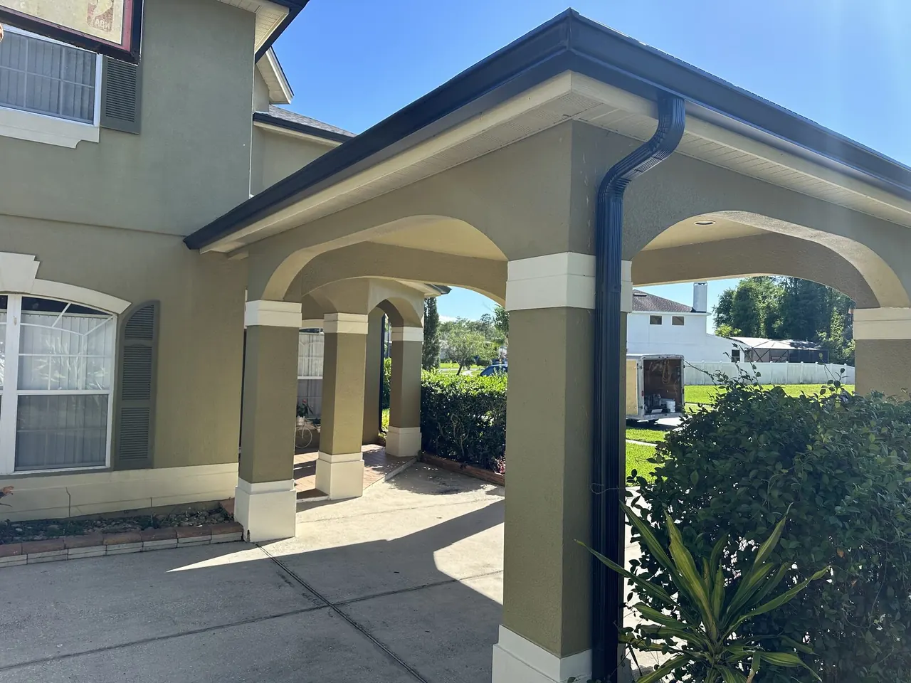 Black gutter and downspout on a covered entry with columns