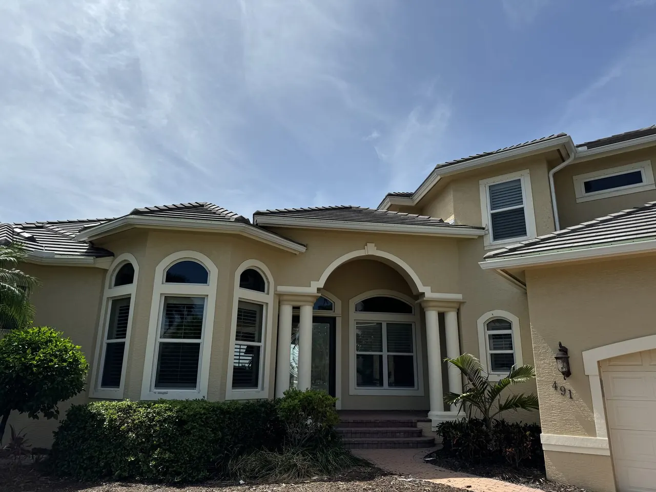 Tile roof home with white gutters over the garage and entry