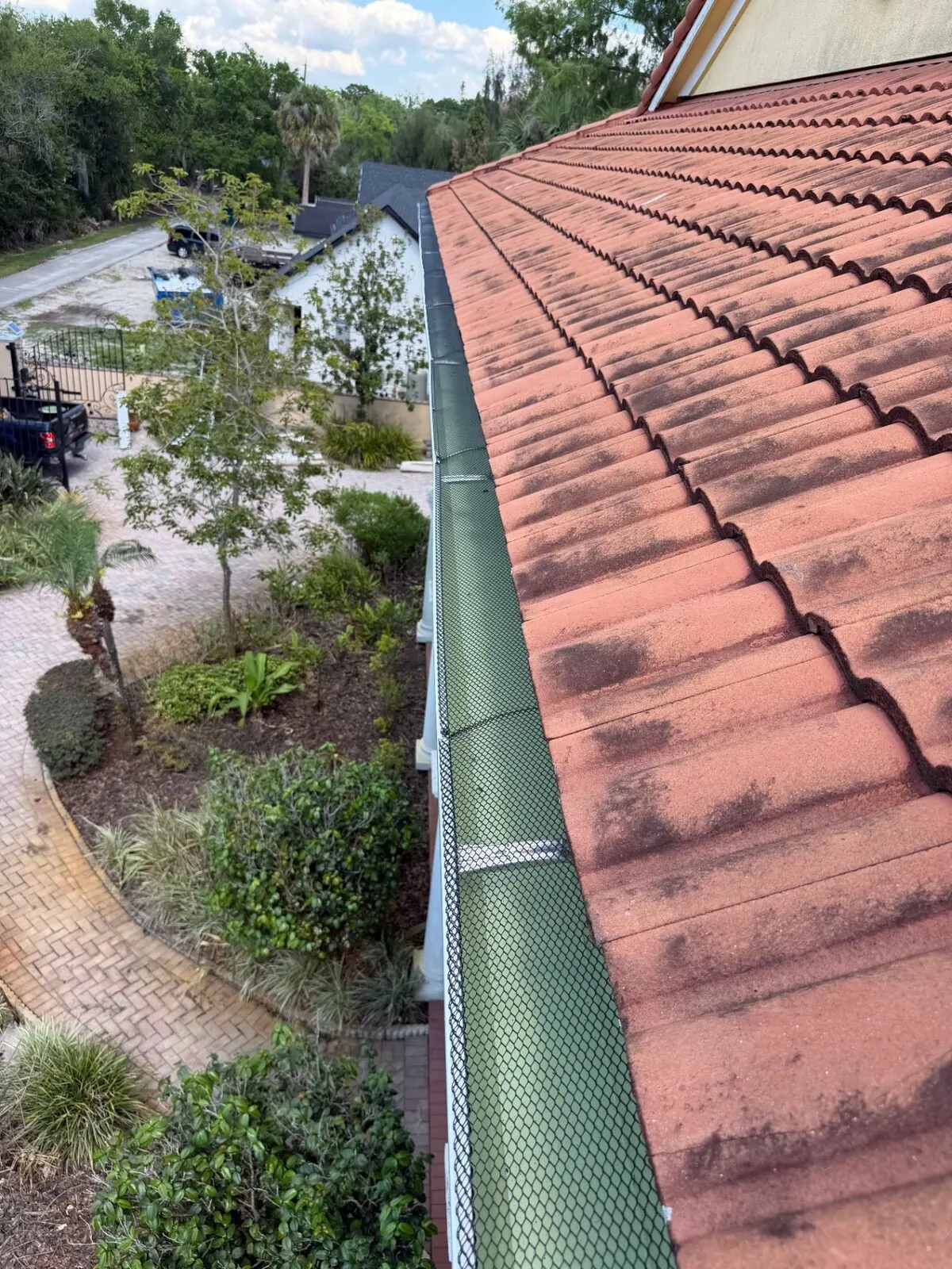 Close-up of a gutter guard installed under tile roofing