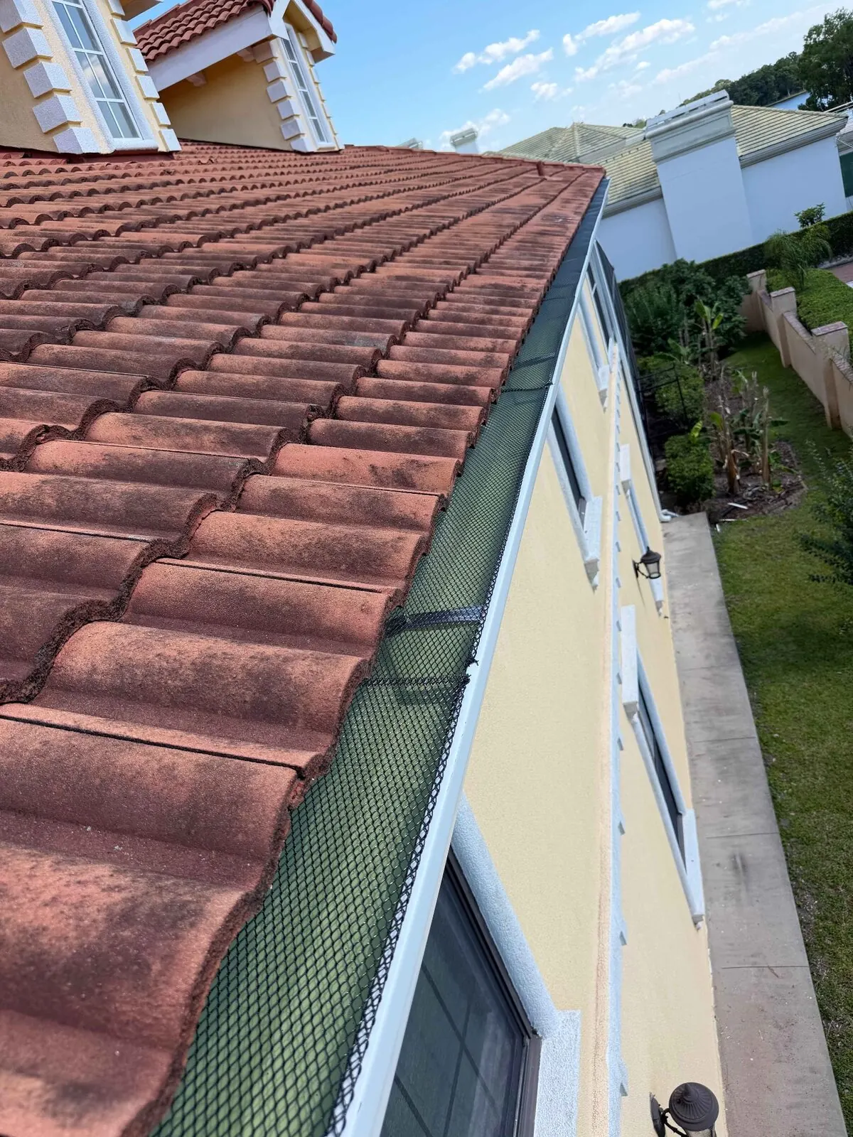 Gutter guard running along a tile roof edge