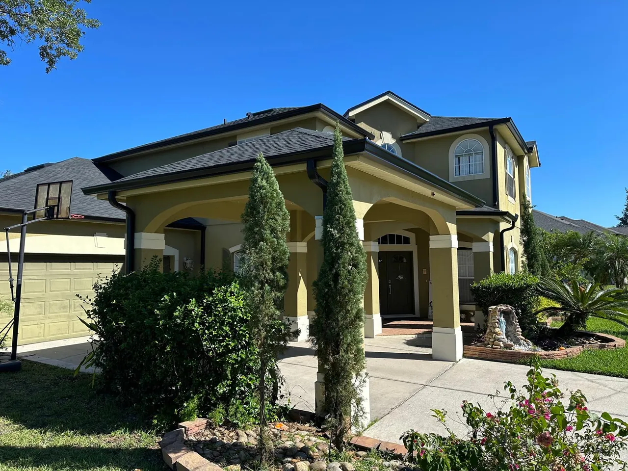 Two-story yellow stucco home with a covered entry and new gutters