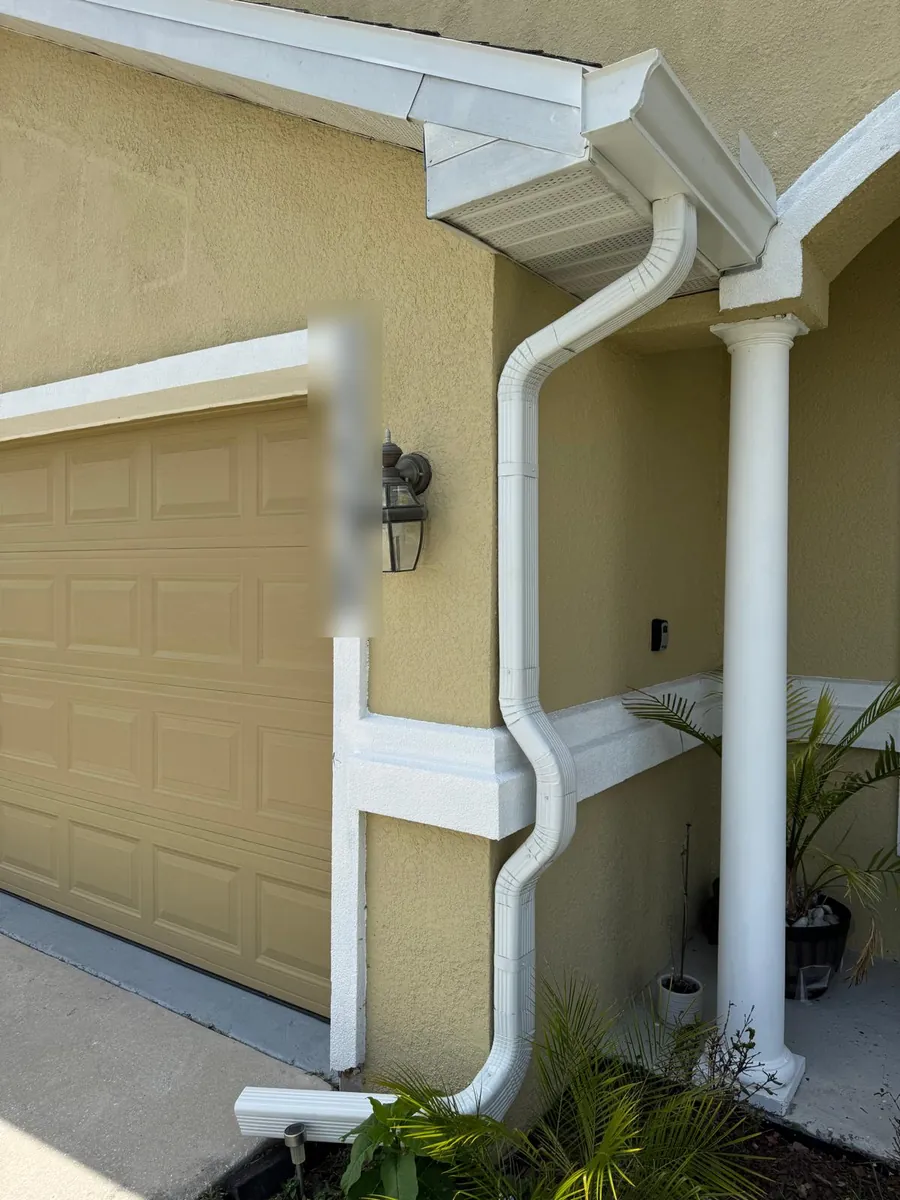 White downspout routed around a garage and porch column