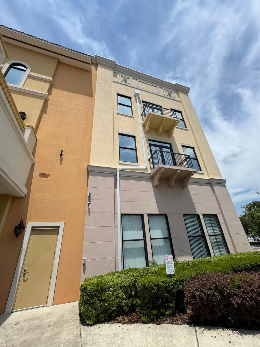 Four-story stucco commercial building with white downspouts