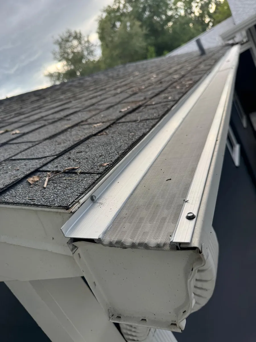 Close-up of a gutter guard installed along a shingle roof