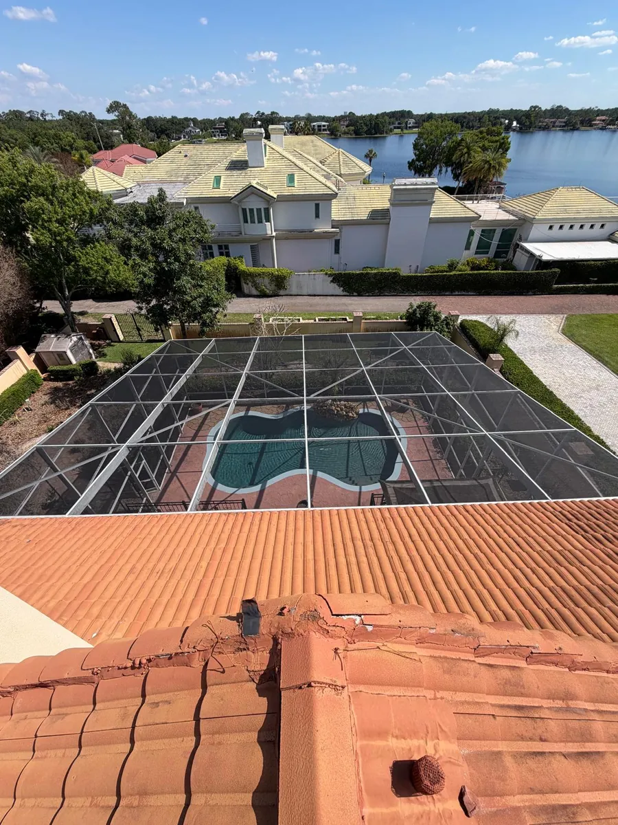 Pool screen enclosure seen from a tile roof with a lake behind