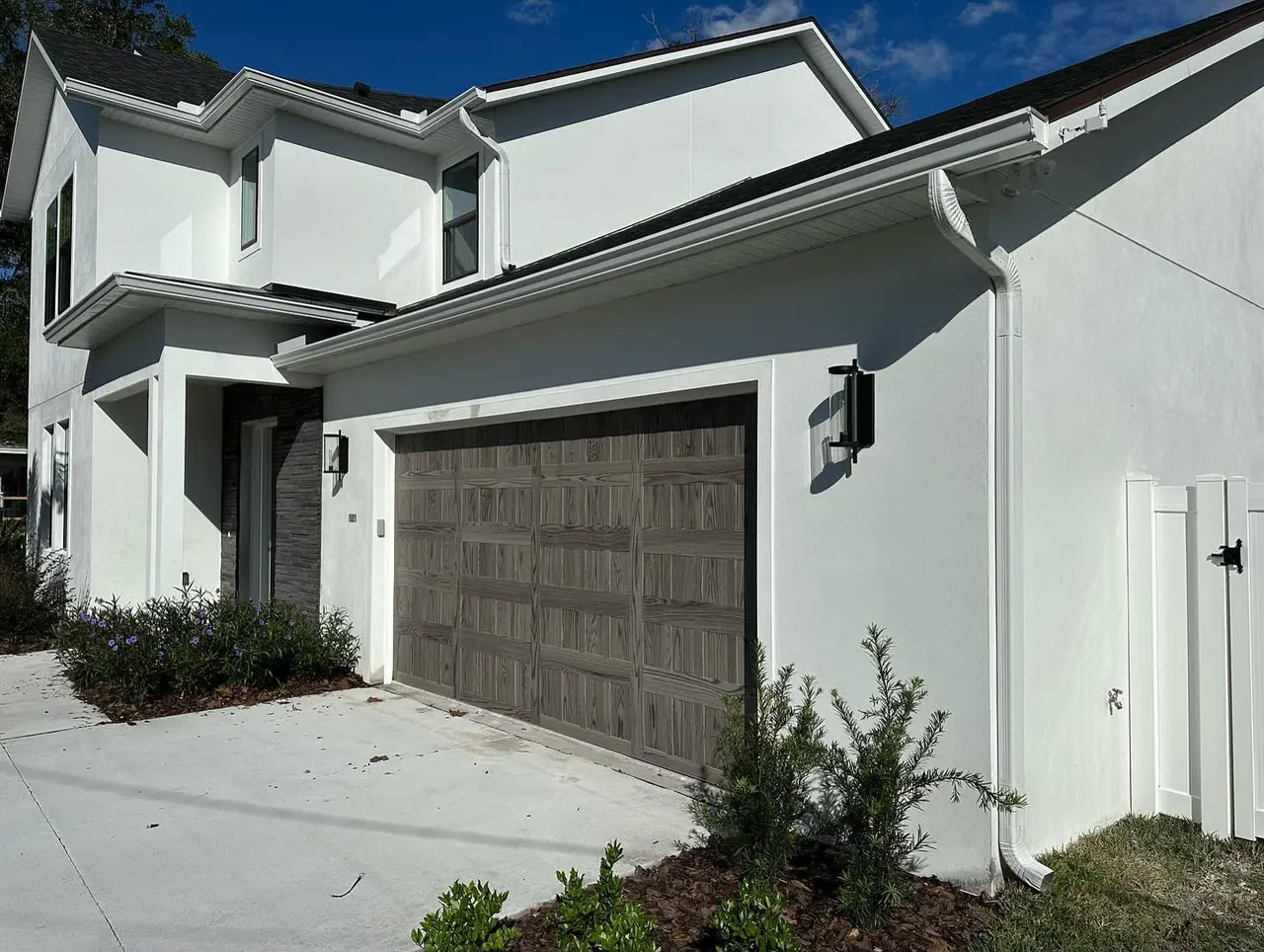 Contemporary white home with gutters and a dark garage door