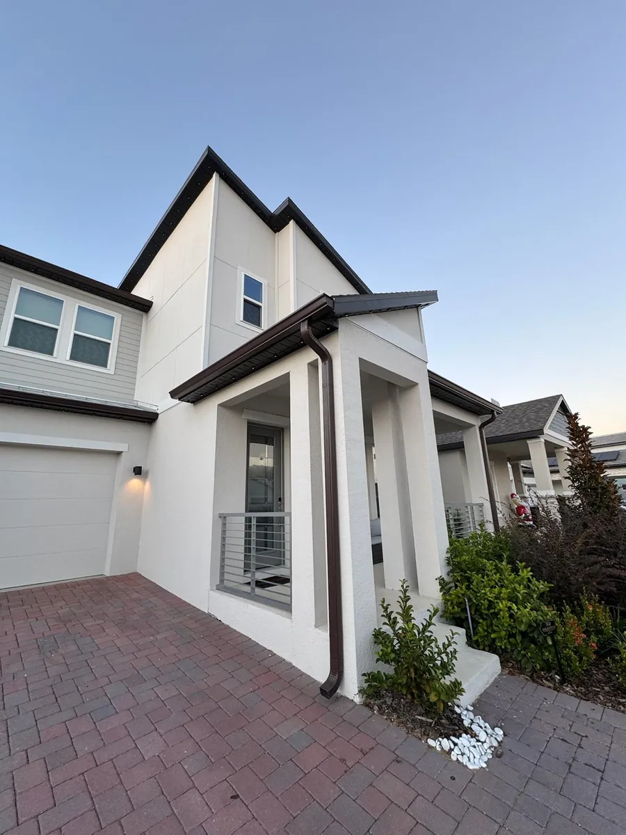 Modern white two-story home with bronze gutters and downspouts