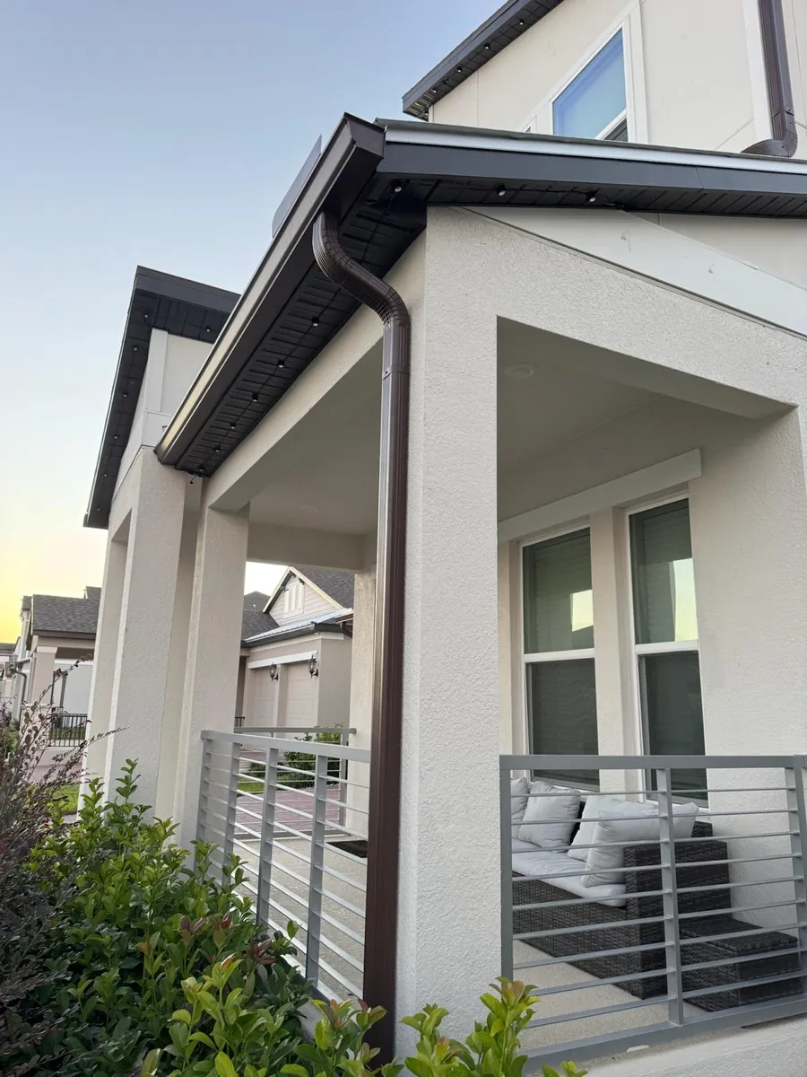 Bronze downspout running down a covered porch column on a modern home