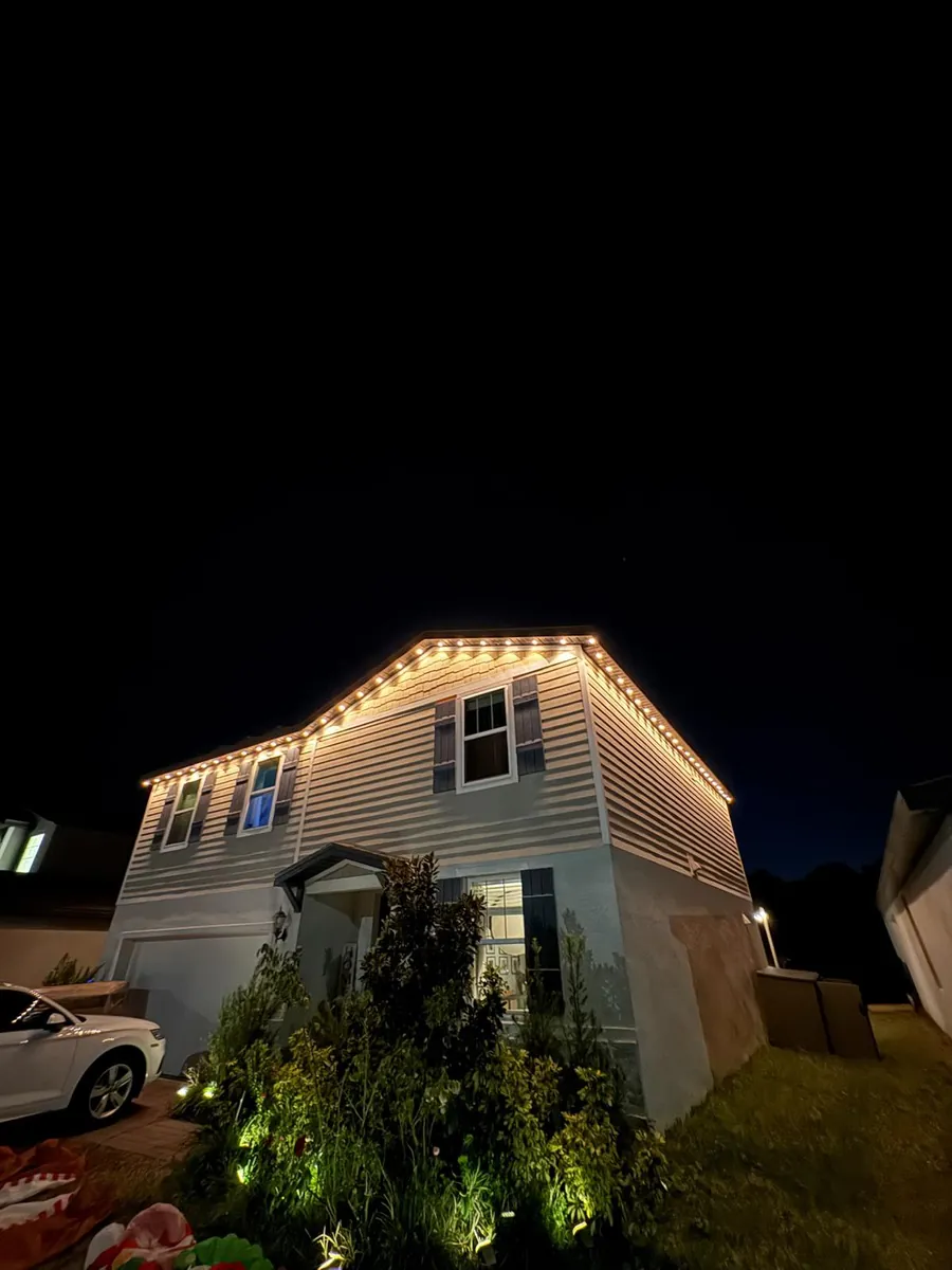 Two-story home at night with a warm white roofline and gable lights