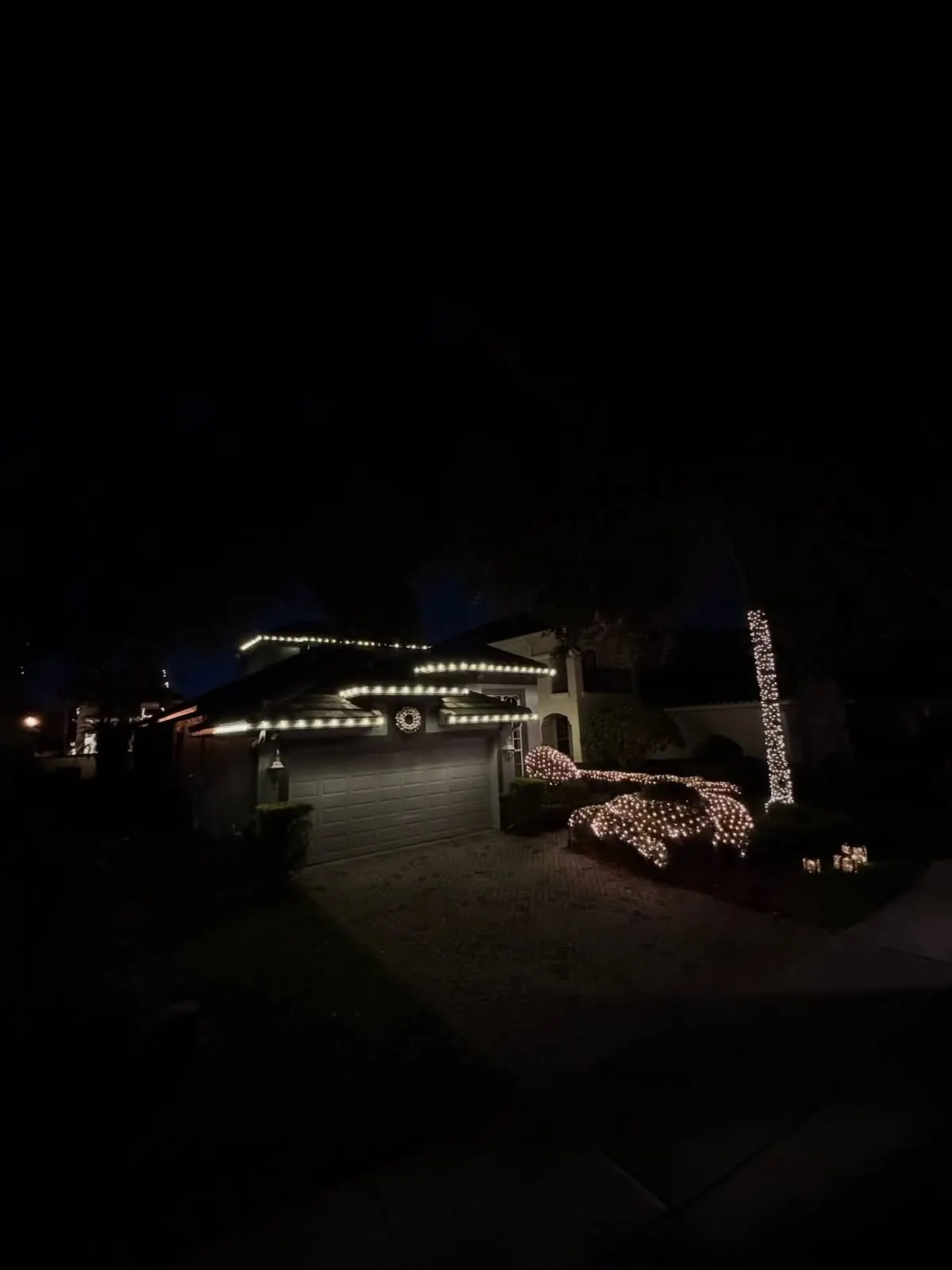 Home at night with warm white roofline and landscape Christmas lights