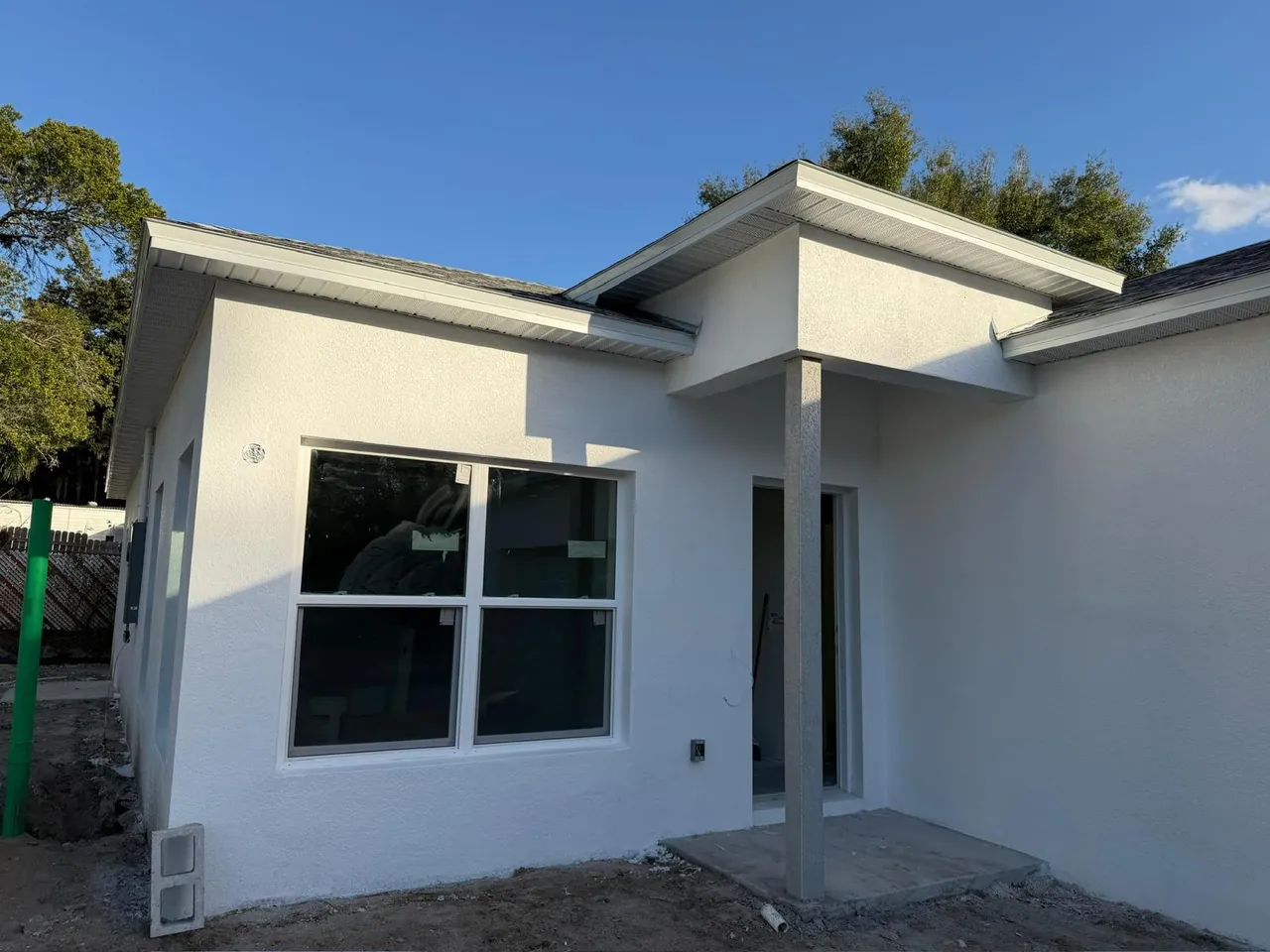 White stucco home with finished soffit and fascia over a covered entry